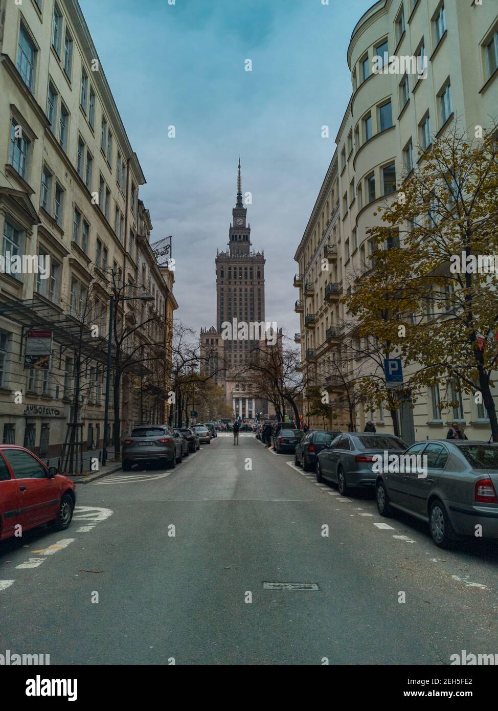 Varsavia Novembre 10 2019 Palazzo della Cultura e della Scienza al fine della strada e uomo in piedi tra due lunghi affittuario case Foto Stock