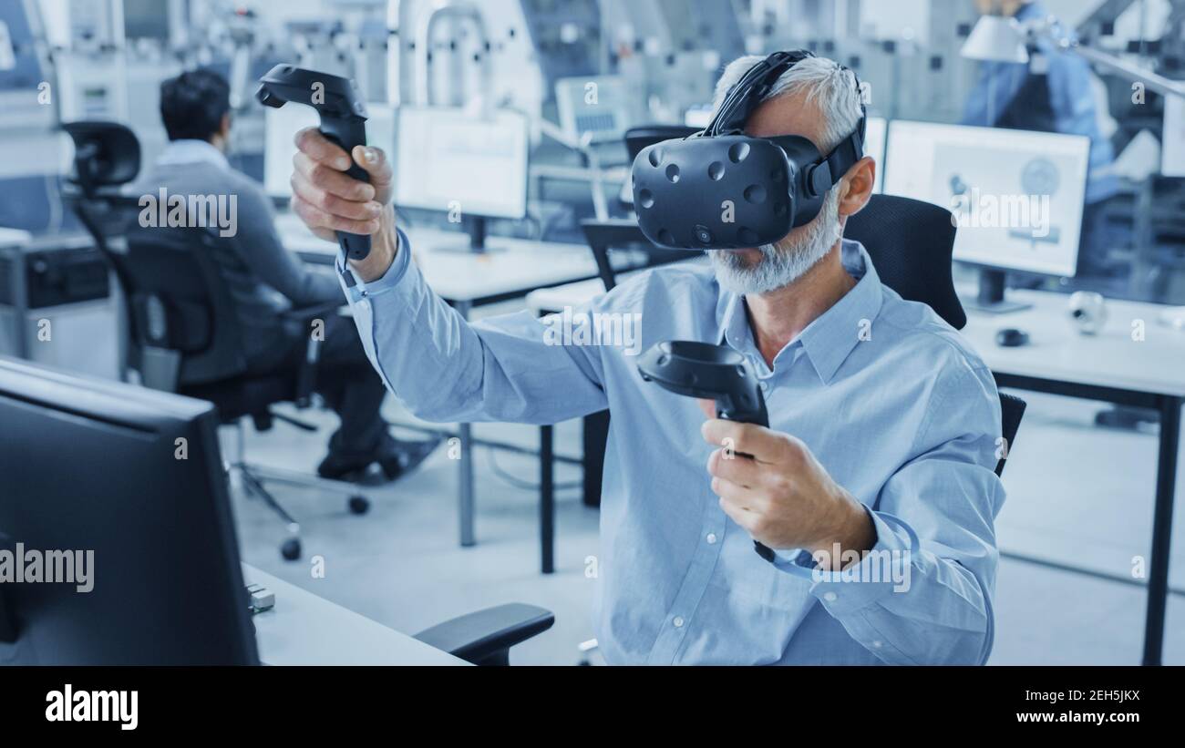 Industrial Design Engineer che indossa il visore per realtà virtuale e i controller di tenuta, utilizza la tecnologia VR per la progettazione industriale e lo sviluppo Foto Stock