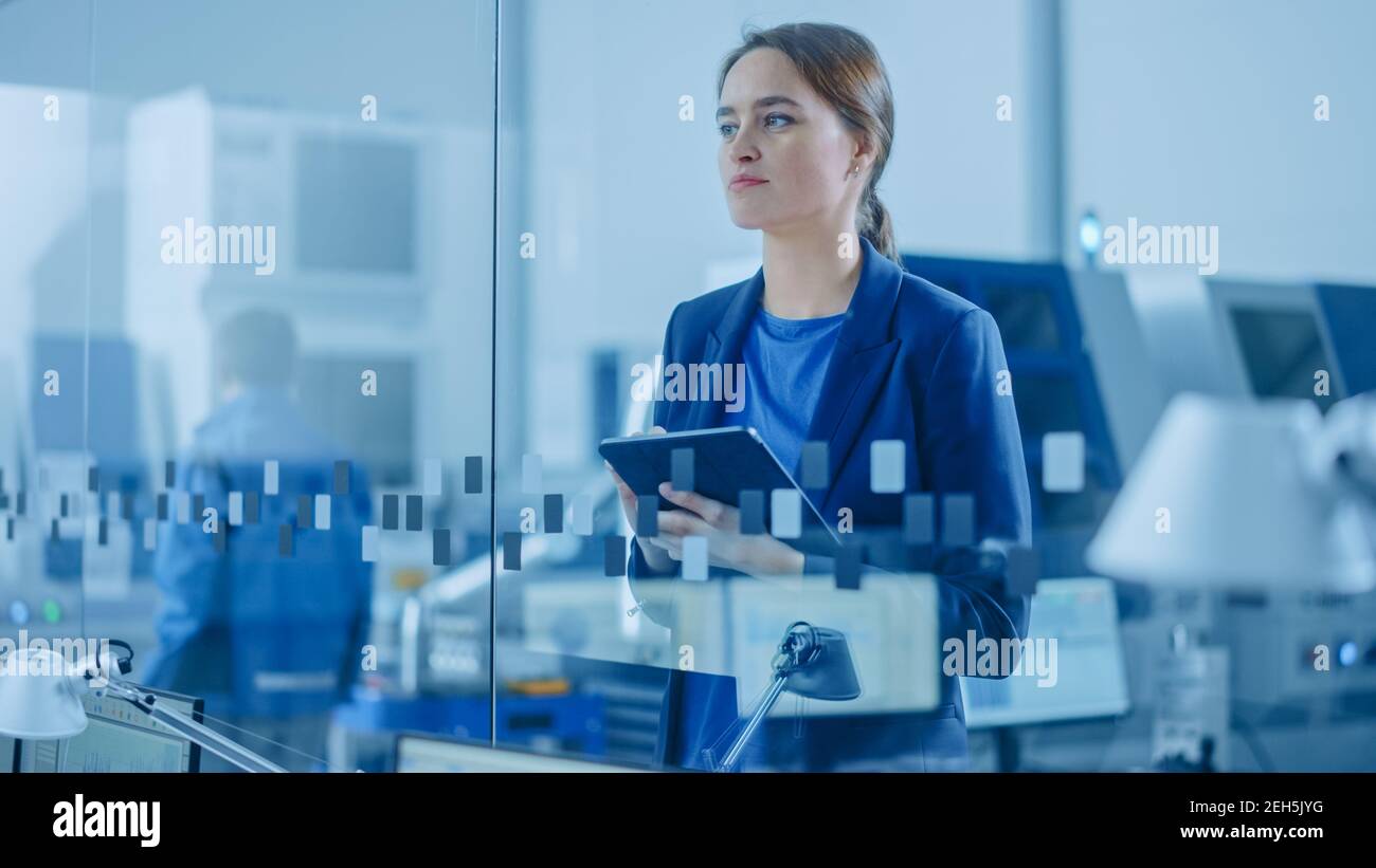 Modern Factory Office: Ritratto di giovane e fiduciosa Ingegnere industriale femminile Standing and Holding Digital Tablet. Ufficio industriale con Foto Stock