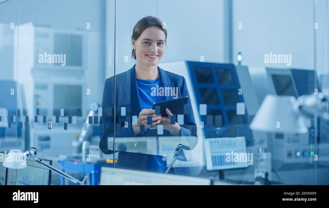 Modern Factory Office: Ritratto di giovane e fiduciosa Ingegnere industriale femminile Standing and Holding Digital Tablet. Ufficio industriale con Foto Stock