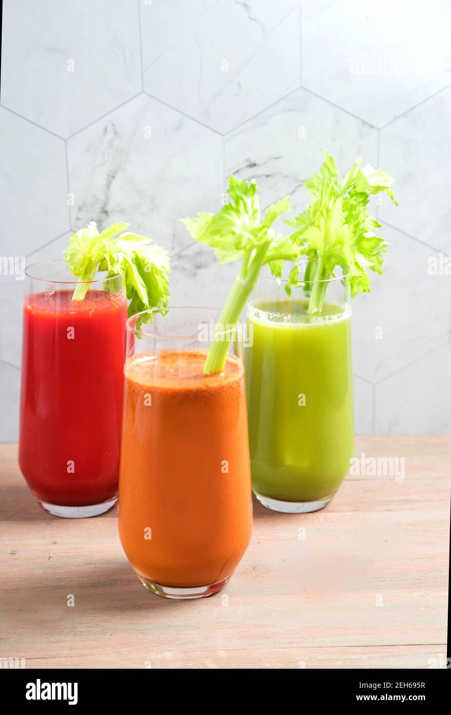 Tre bicchieri di succhi naturali di verdure fresche, pomodori, sedano e carote con foglie di sedano. Bevande salutari, spazio copia Foto Stock