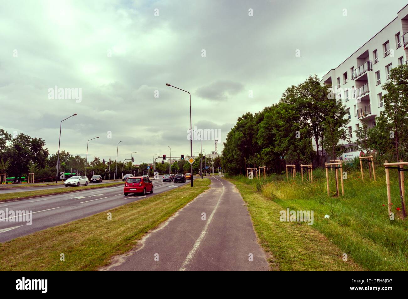 POZNAN, POLONIA - 13 giu 2019: Strada asfaltata con auto di guida accanto al verde erba e un percorso in bicicletta nel quartiere di stare Zegrze in una giornata nuvolosa. Foto Stock