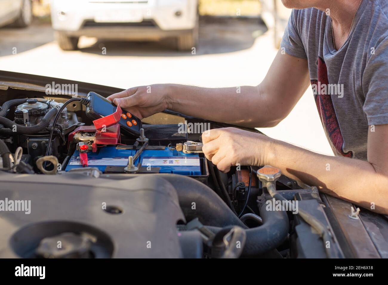 Riparazione e ispezione della batteria dell'auto. L'operatore misura la tensione e la capacità della batteria con un tester. Servizio auto. Foto Stock