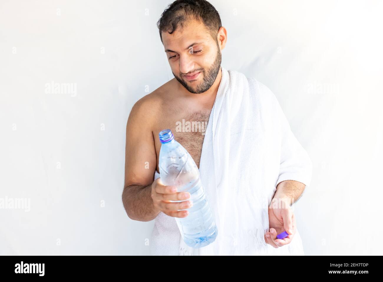 Uomo musulmano che beve dell'acqua dopo la conclusione di haj Foto Stock
