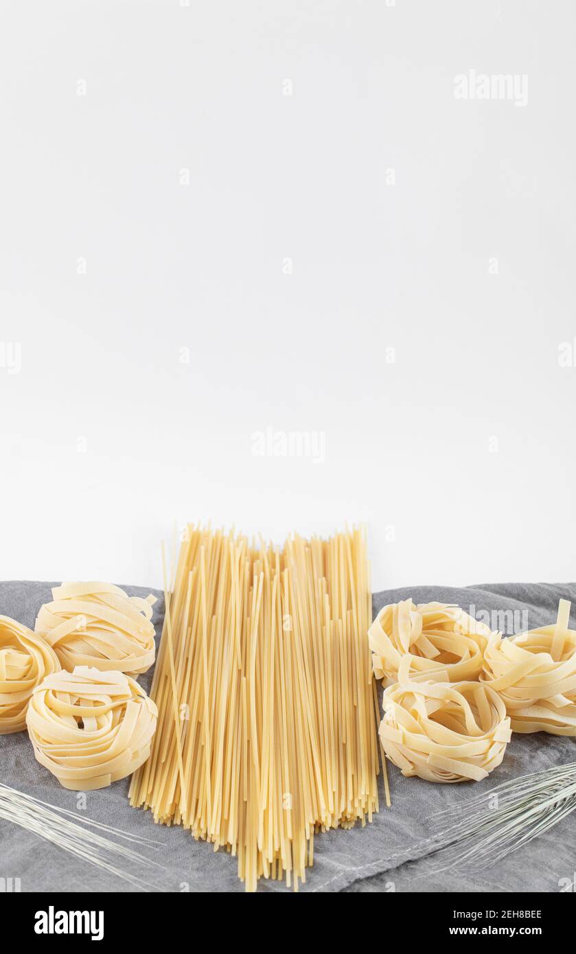 Varietà di pasta cruda su tovaglia grigia Foto Stock