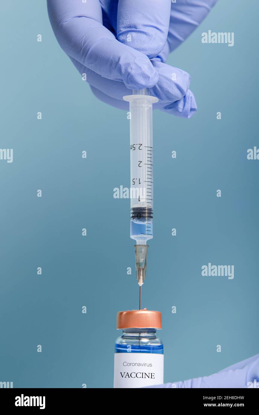 Covid-19 Vaccine - medico con guanto chirurgico contenente un flaconcino del vaccino Foto Stock