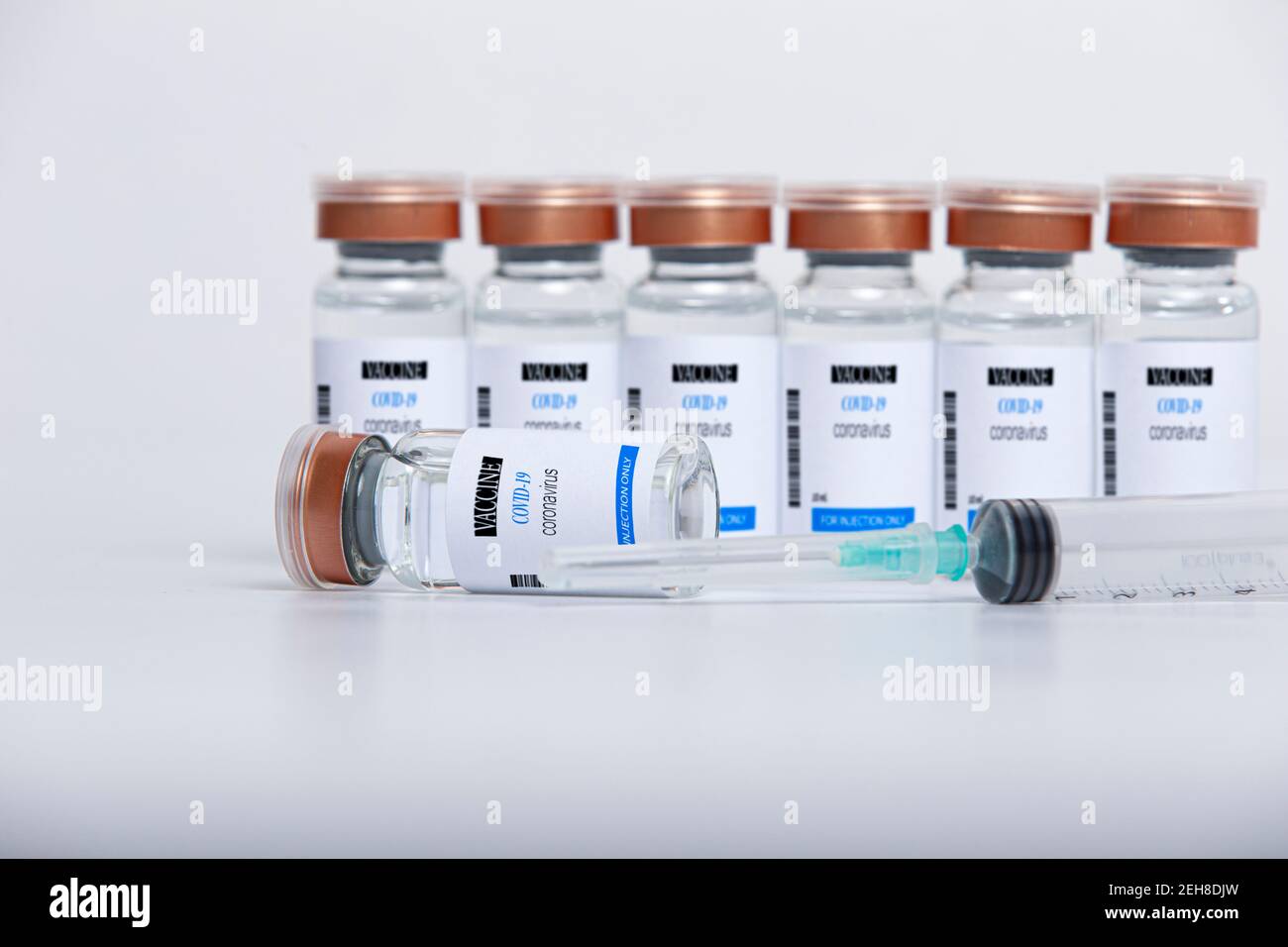 Flaconcini di vetro trasparente con vaccino COVID-19 e siringa su bianco sfondo Foto Stock
