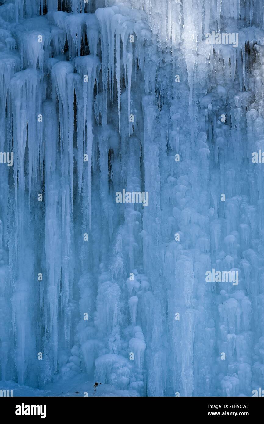 Belle strutture ghiacciate di una cascata ghiacciata, graziose iciclette che formano un interessante modello su una roccia scura, creando un freddo umore di mangia Foto Stock