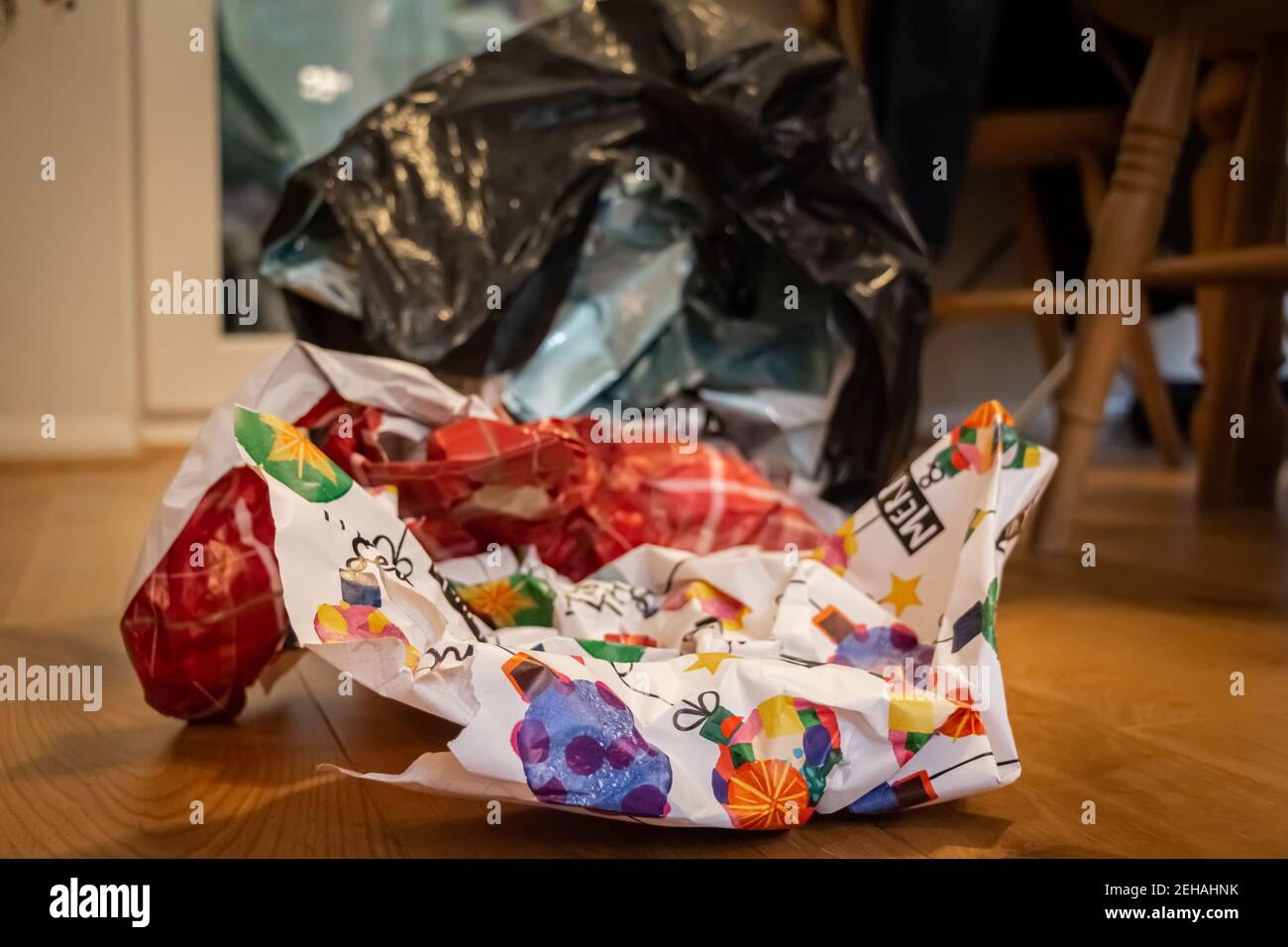 Natale che avvolge lo spreco di carta in un rivestimento del contenitore che giace su un pavimento di legno il giorno di Natale, dopo che i regali erano stati aperti Foto Stock