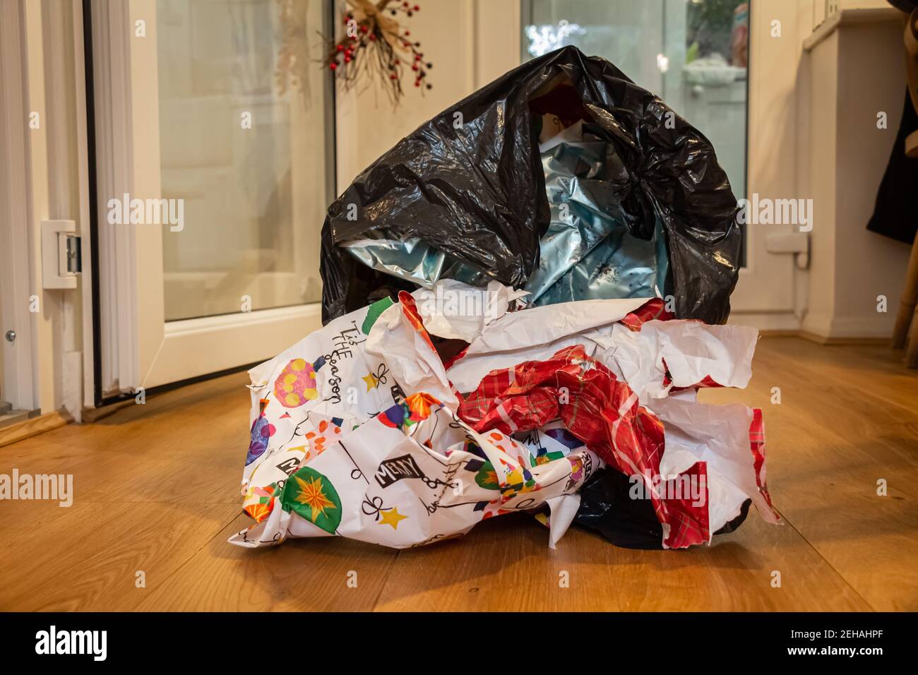 Natale che avvolge lo spreco di carta in un rivestimento del contenitore che giace su un pavimento di legno il giorno di Natale, dopo che i regali erano stati aperti Foto Stock