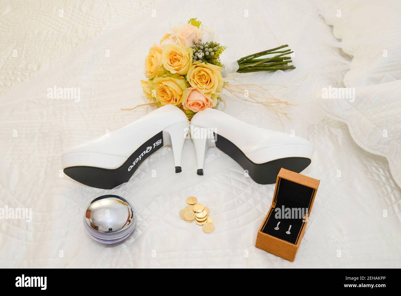 Accessori da sposa. Bouquet di rose gialle, scarpe con le parole se voglio, soldi seri, orecchini e profumo il giorno delle nozze in Spagna. Foto Stock