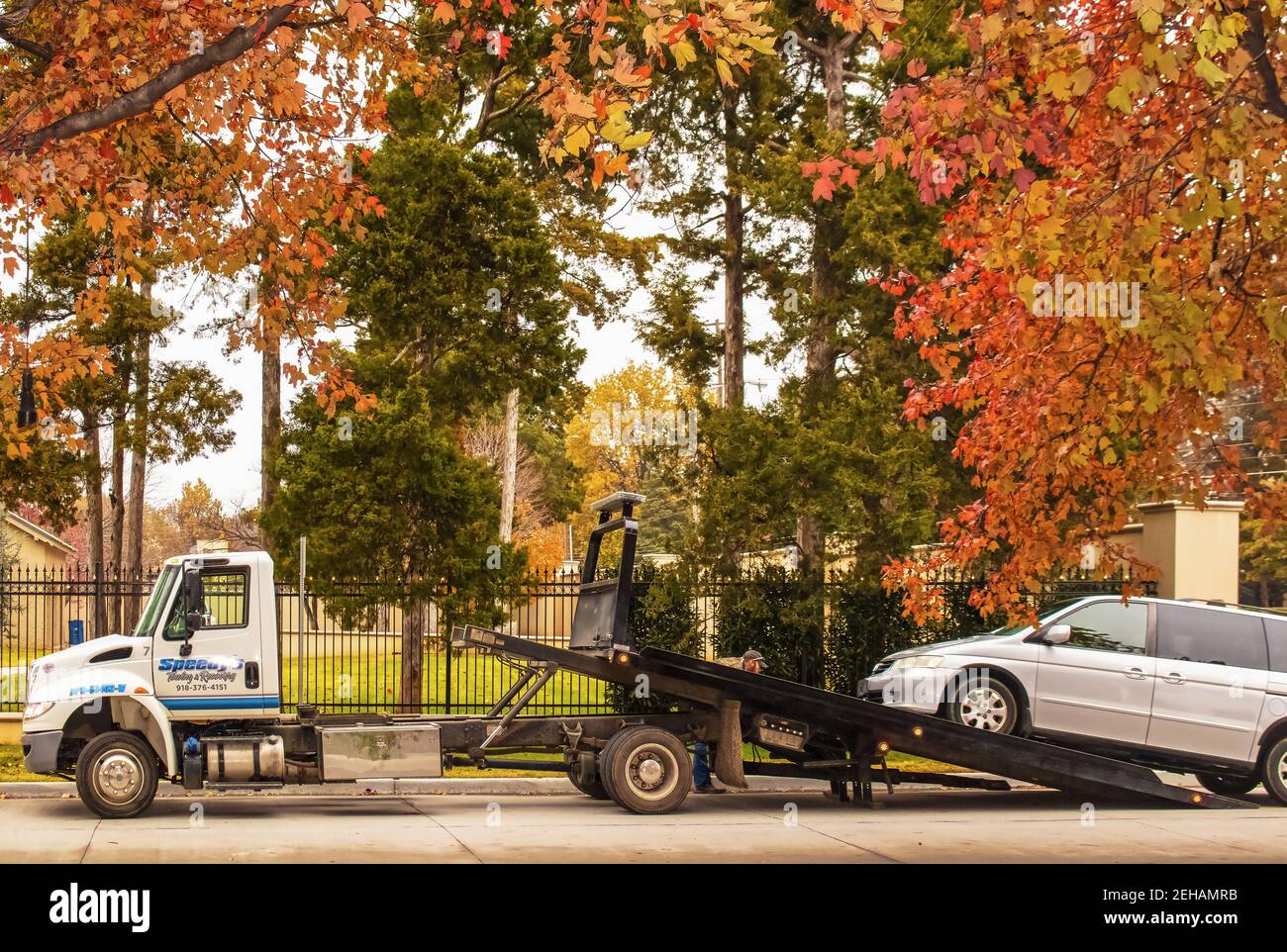 2018 11 18 Tulsa USA traino del carrello con l'operatore che effettua le regolazioni a. van è caricato sul rimorchio sulla strada su una bella e colorato giorno d'autunno di fronte Foto Stock
