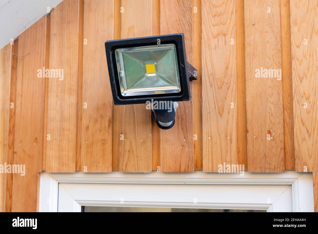 Luce del sensore di allagamento da giardino fissata a una parete di legno sopra una porta Foto Stock