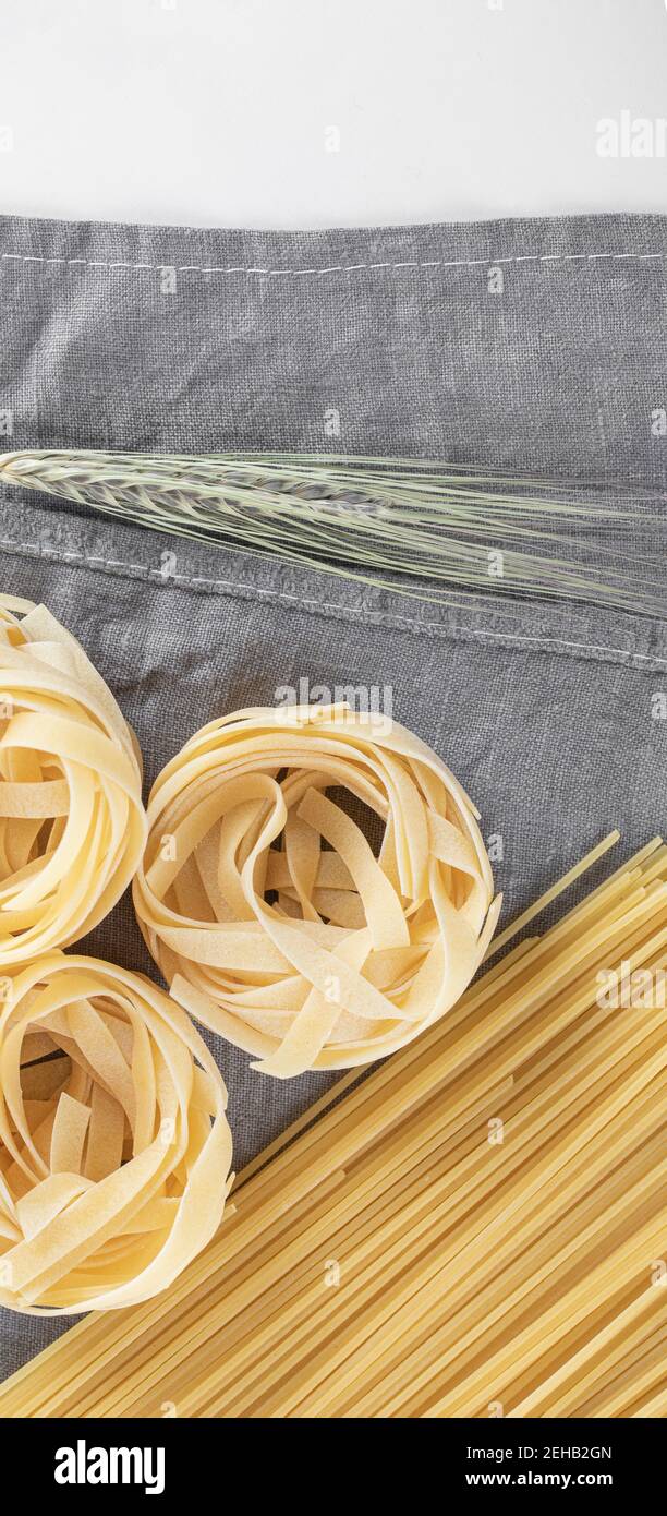 Varietà di pasta cruda su tovaglia grigia Foto Stock