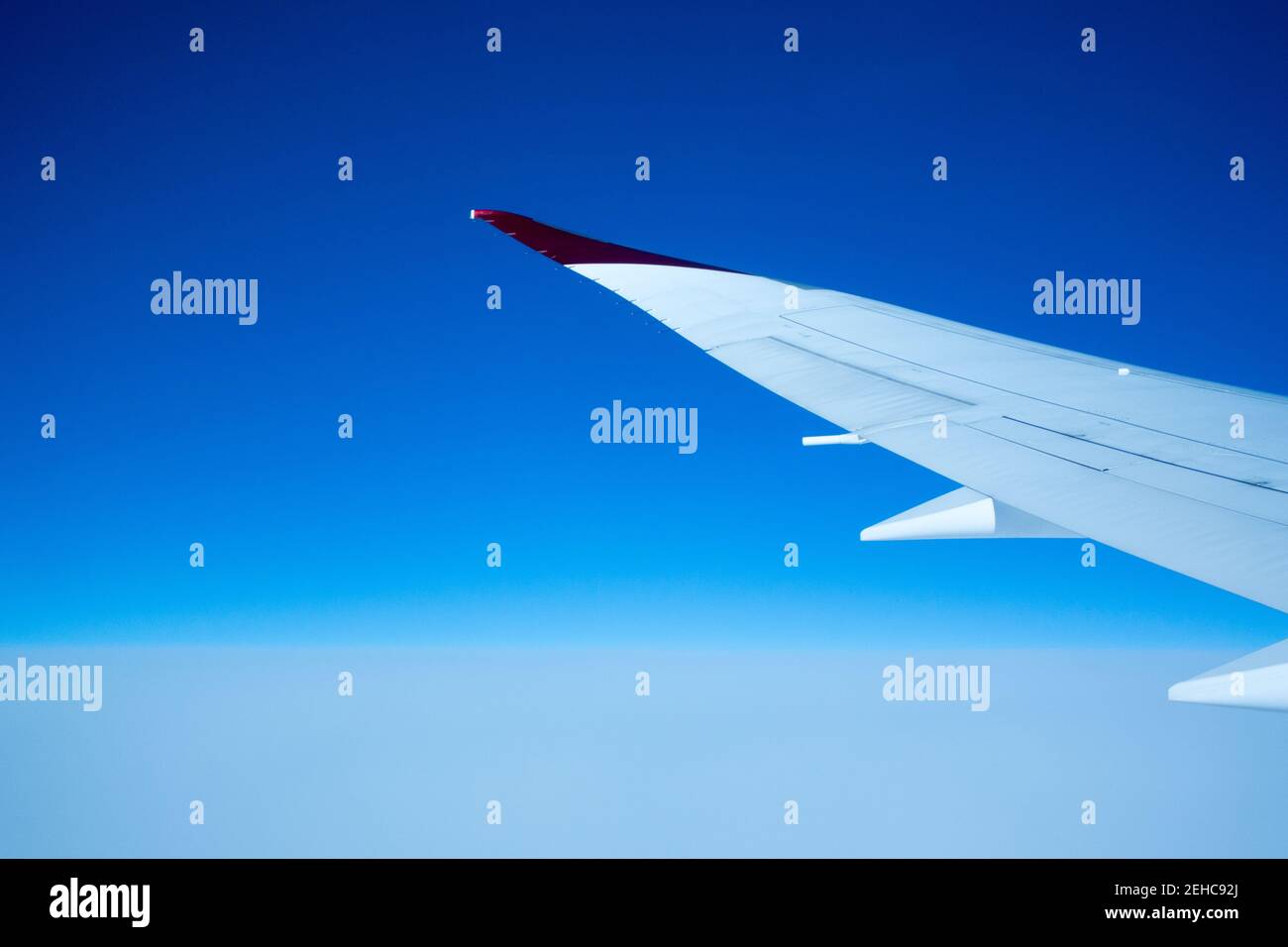 Concetto di Air Travel con ala di aeroplano che si estende in un bianco e cielo blu Foto Stock