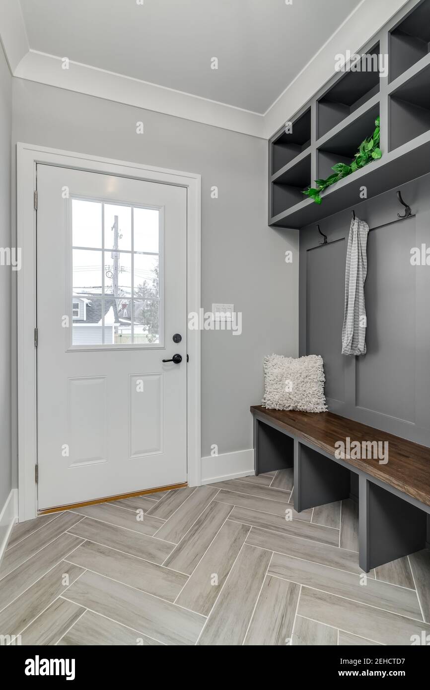 Una foto dettagliata di un ingresso grigio di un vano fanghroom con panca, ganci per cappotti e ripostiglio sopra. Foto Stock