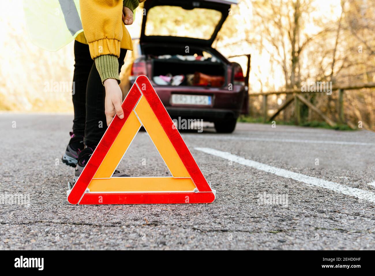 Persona non riconoscibile tagliata che mette giù il segnale di triangolo di avvertimento della strada sopra autostrada Foto Stock
