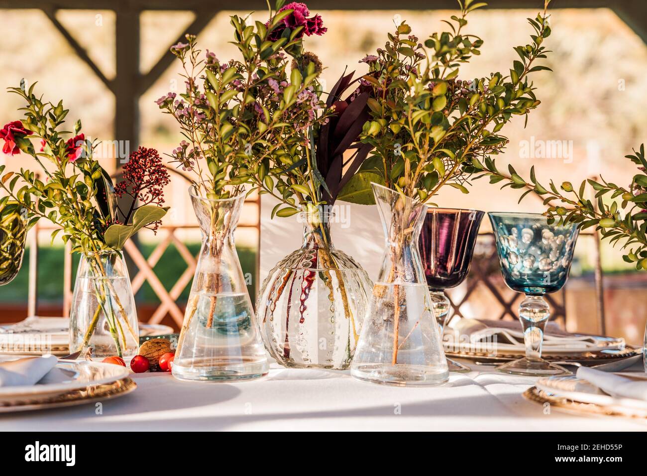 Primo piano di vasi in vetro trasparente con mazzi di fiori freschi posto sul tavolo per l'evento Foto Stock