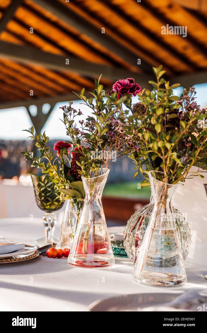 Primo piano di vasi in vetro trasparente con mazzi di fiori freschi posto sul tavolo per l'evento Foto Stock