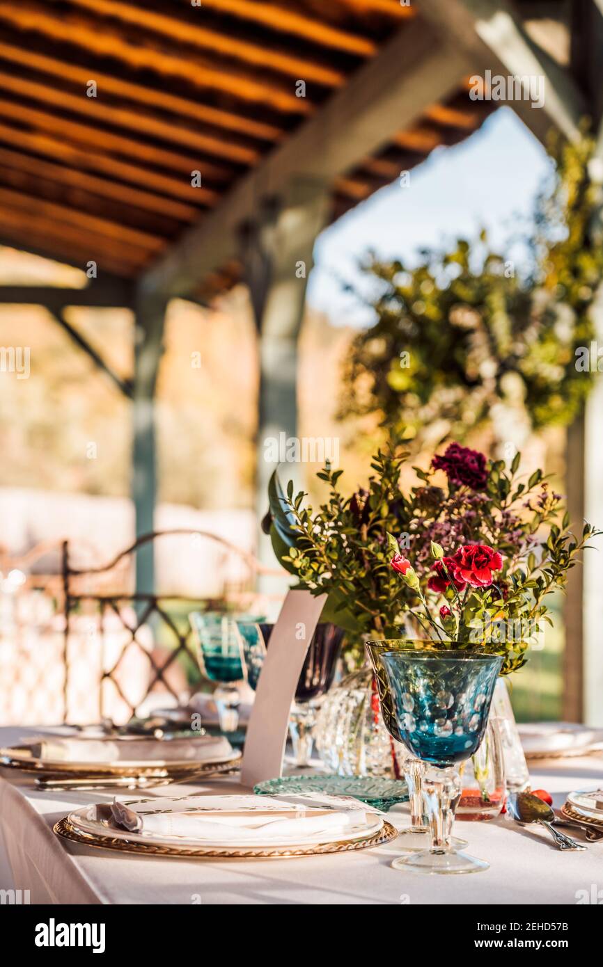 Primo piano del tavolo festivo servito con bicchieri di cristallo, tovagliolo posate su piatto vicino mazzo di fiori freschi per il matrimonio e. scheda menu Foto Stock