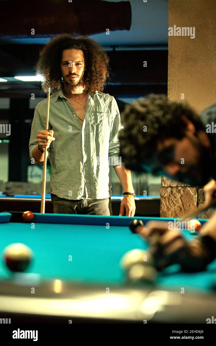 Uomo etico serio con cue competere in gioco con il giocatore colpire la palla da biliardo Foto Stock