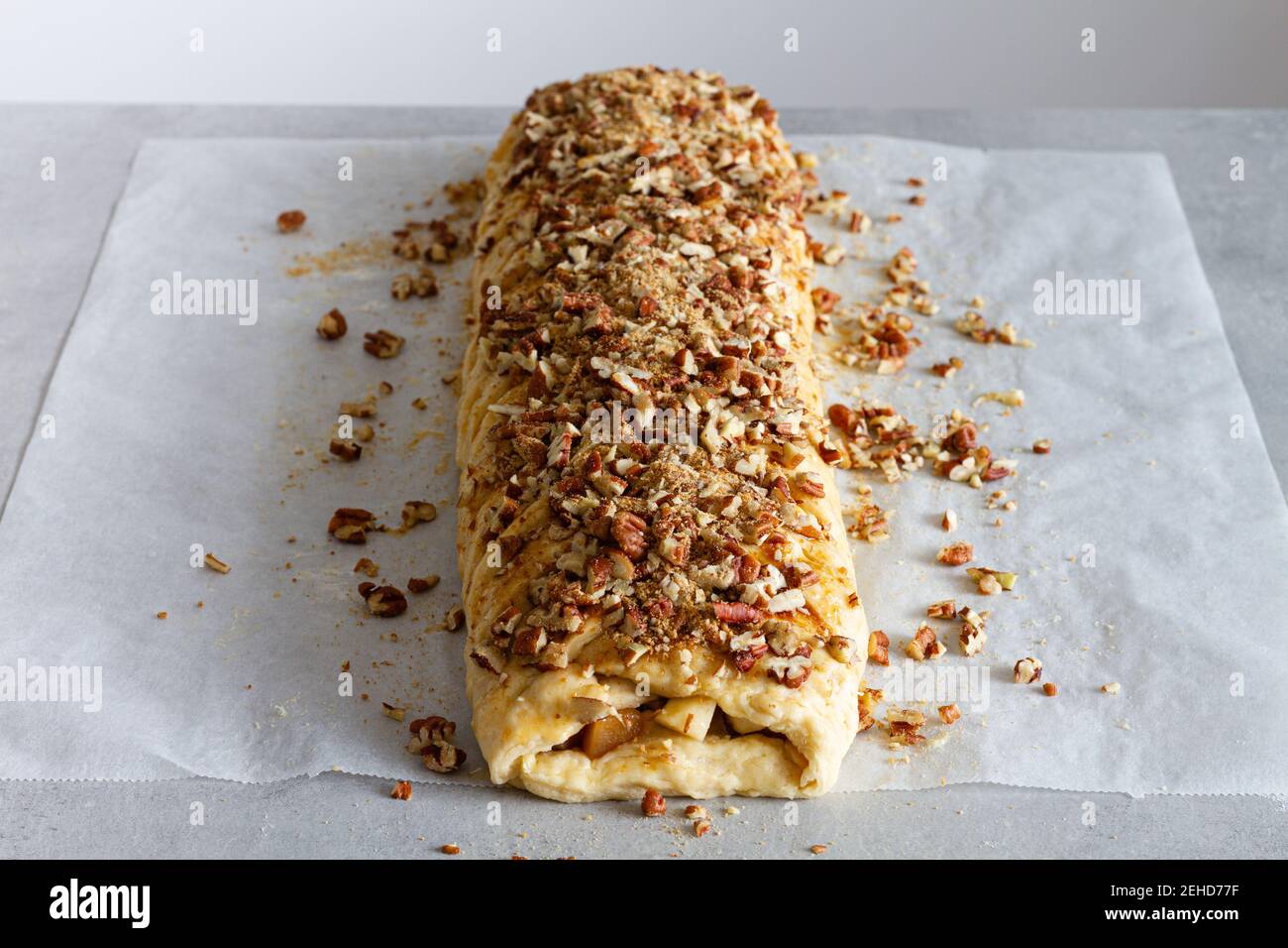 Da sopra gustosa pasticceria di mele con pezzi croccanti di noci sopra carta da forno sul piano di lavoro Foto Stock