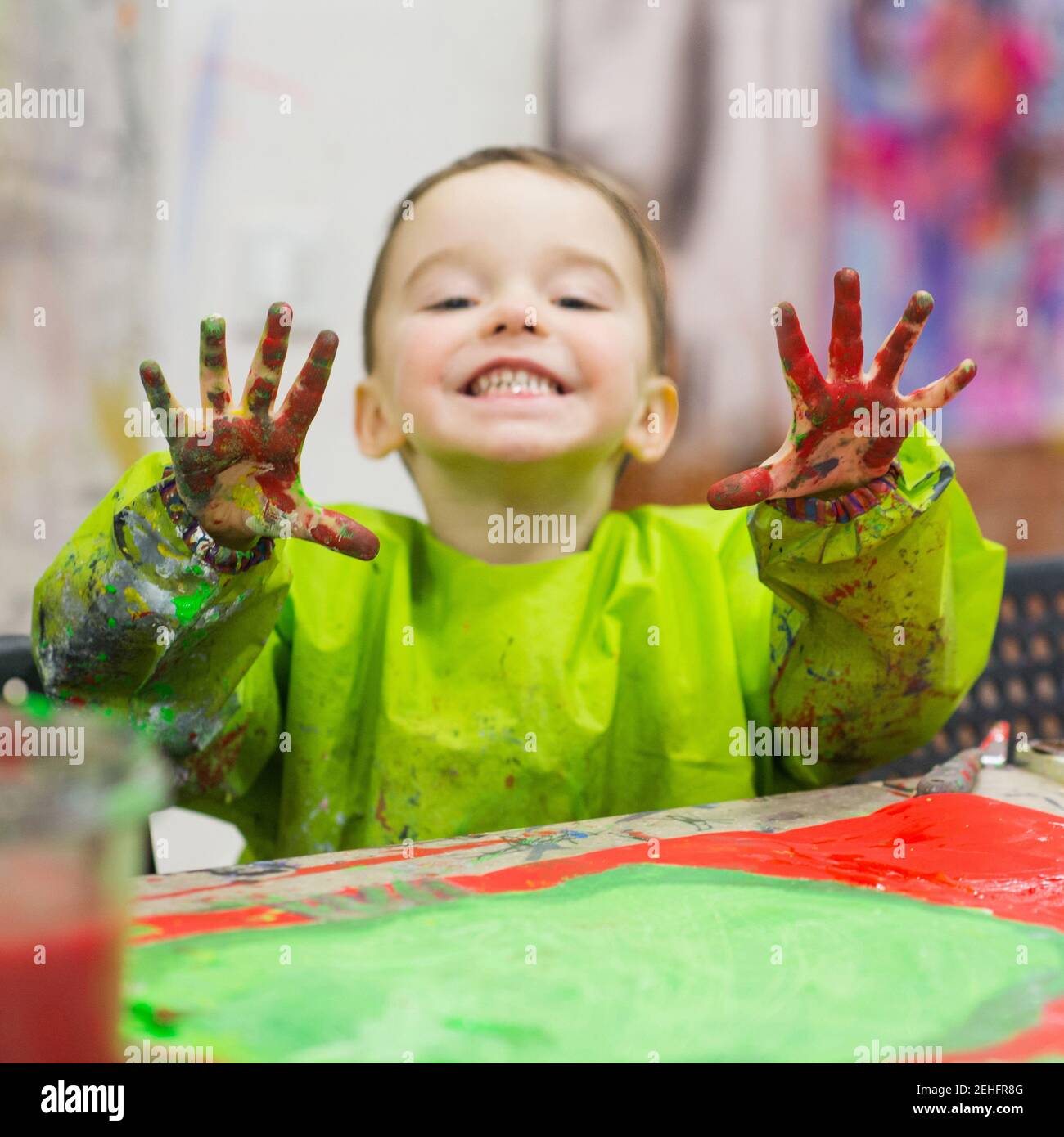 Bambino alla classe d'arte sorridendo felice e mostrandogli palmo colorato Foto Stock