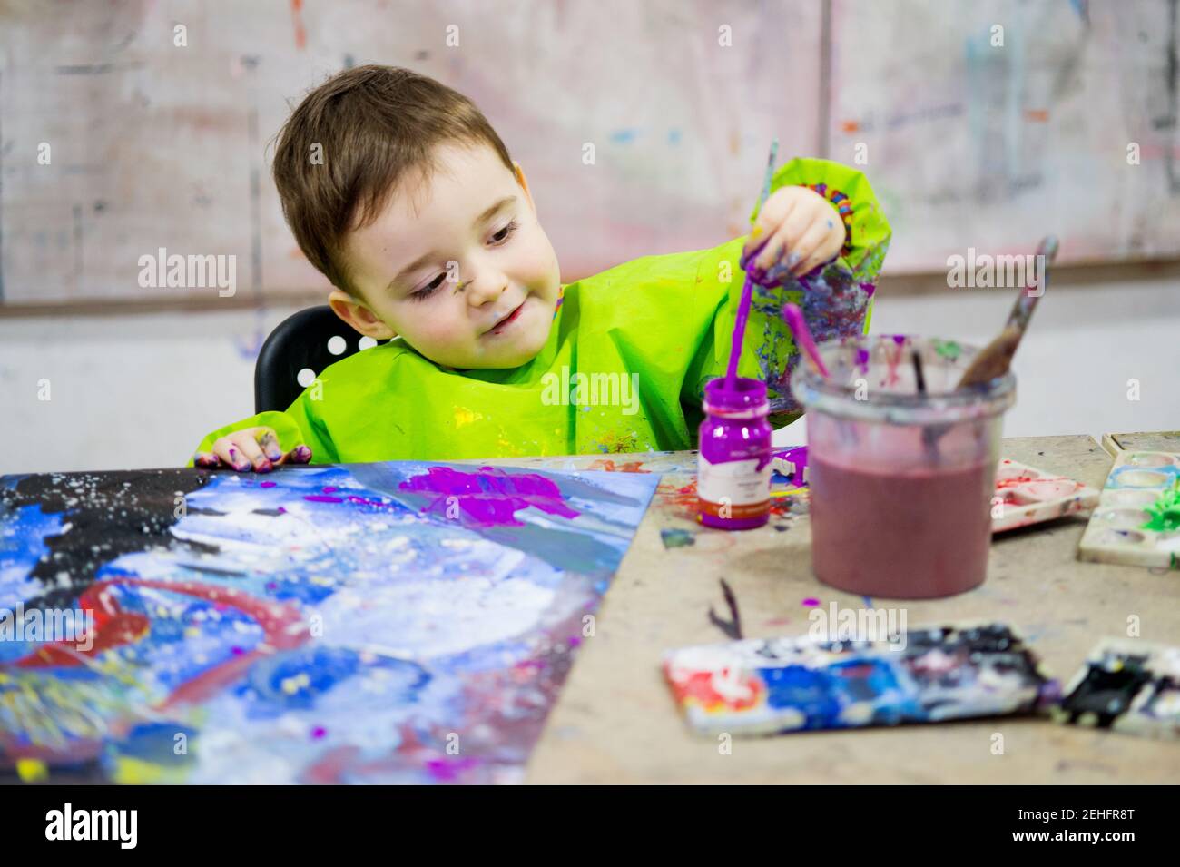 Ritratto di un bambino in aula d'arte pittura con violetto gouache Foto Stock
