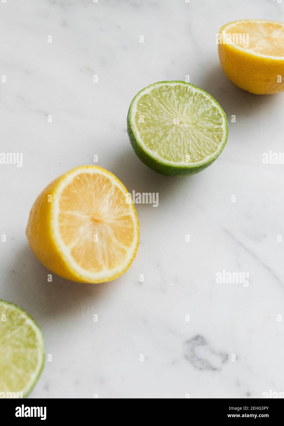 Limone di agrumi fresco, e lime, tagliato su uno sfondo di marmo in una linea Foto Stock