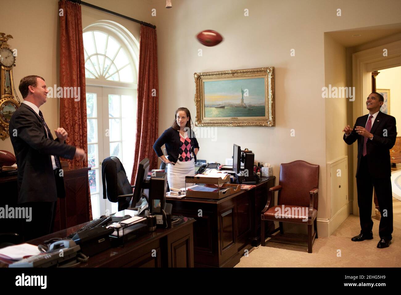 Il presidente Barack Obama lancia un calcio con il direttore di viaggio Marvin Nicholson nell'Outer Oval Office il 26 giugno 2009. La segretaria personale Katie Johnson guarda dalla sua scrivania. Foto Stock