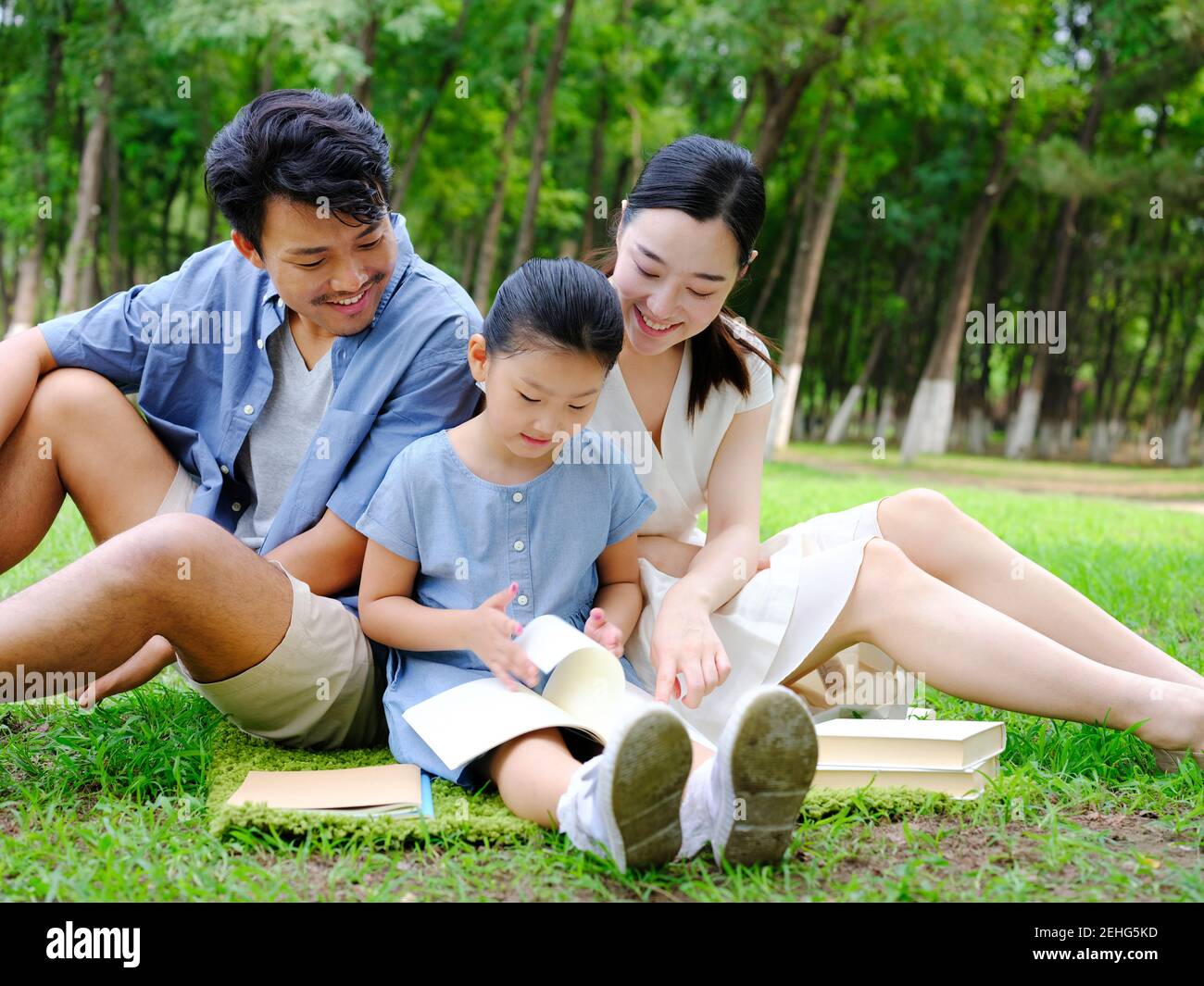 Una felice famiglia di tre persone lo sta leggendo il parco Foto Stock