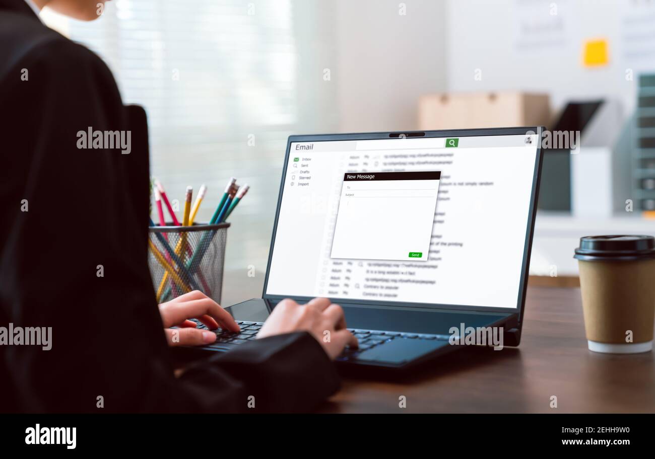 Donna d'affari che scrive un messaggio in linea e-mail sul laptop sul tavolo in ufficio. Foto Stock