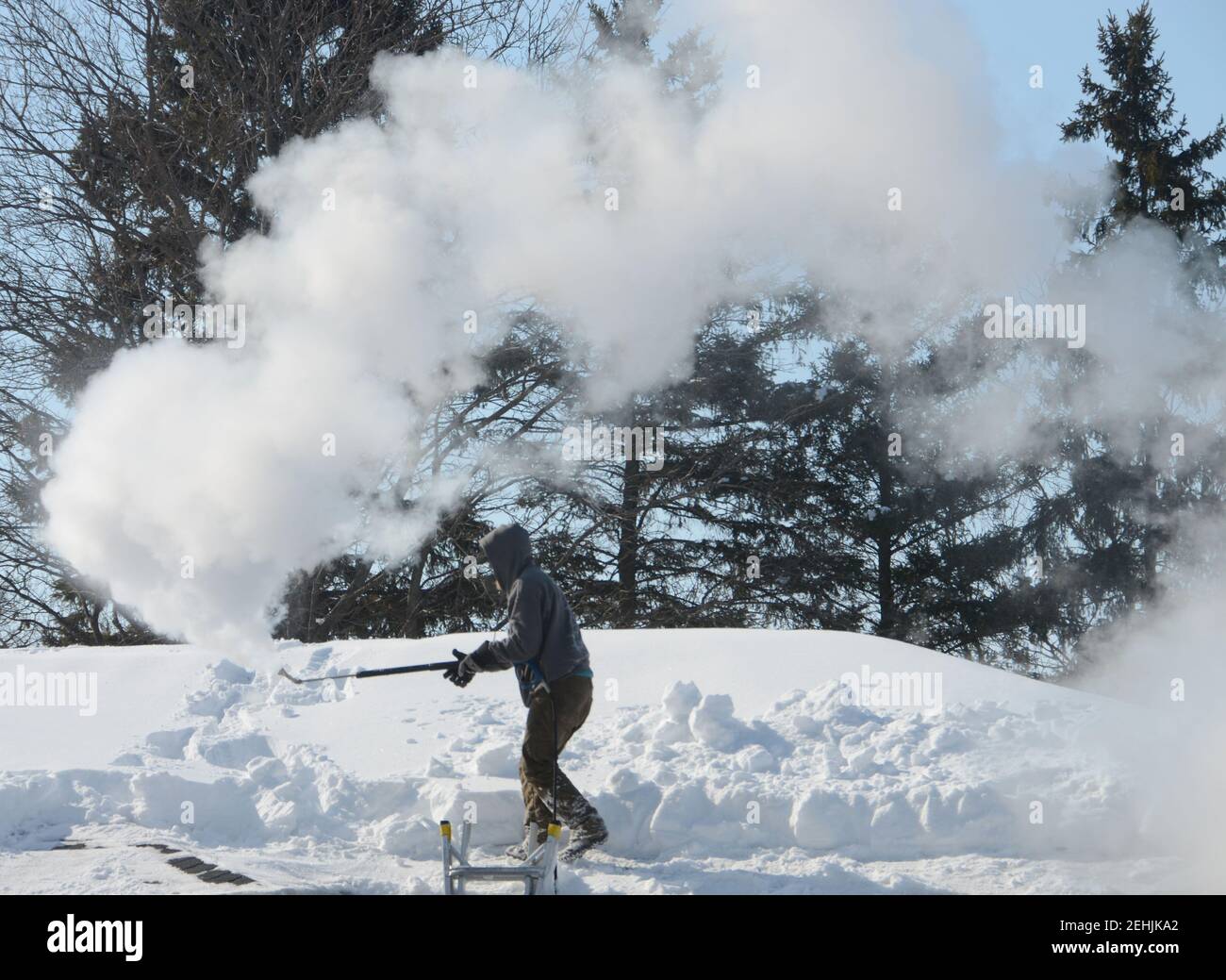 Mount Pleasant, Wisconsin, Stati Uniti. 19 Feb 2021. CHRIS HANSON usa il vapore per pulire la neve dal tetto e grondaie di una casa nel villaggio di Mount Pleasant, Wisconsin Venerdì. La zona ha ricevuto quasi 17 pollici di neve la domenica scorsa e lunedì. (Immagine di credito: © Mark HertzbergZUMA Wire) Foto Stock