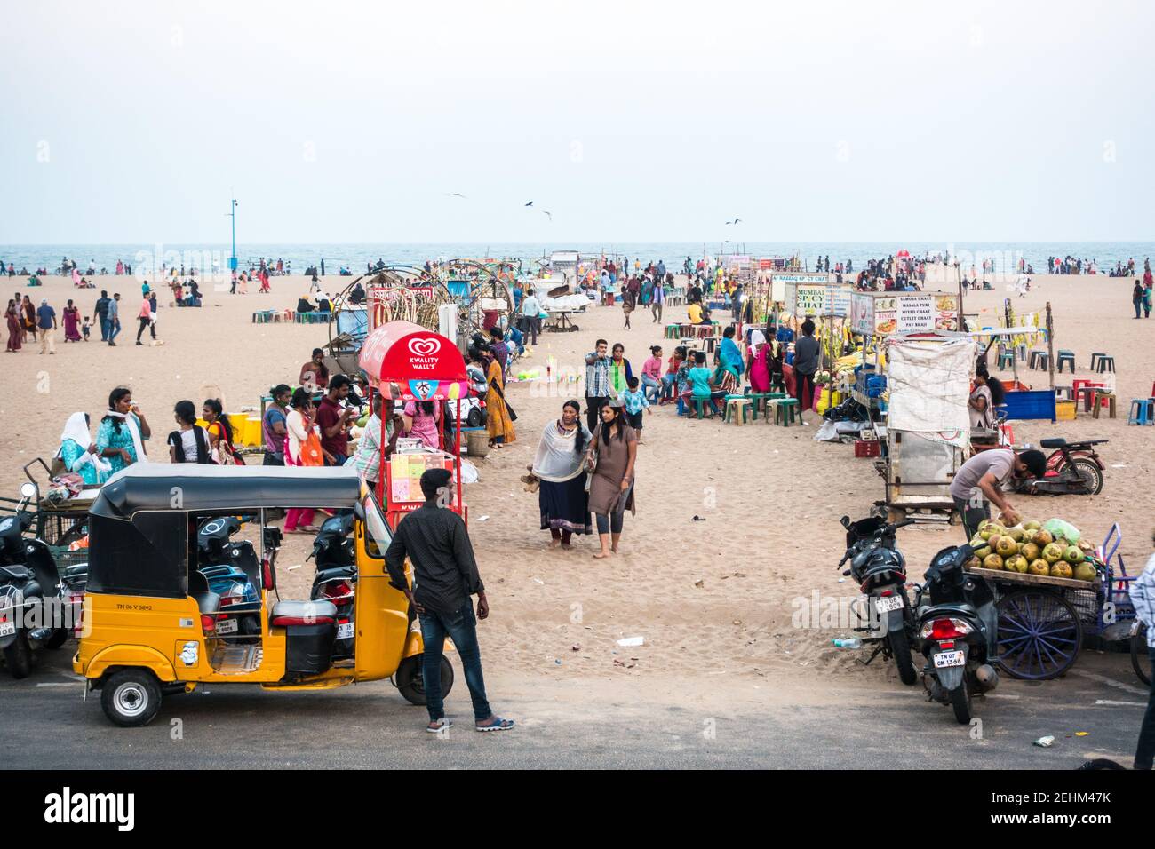 I visitatori della spiaggia di Chennai Marina per godersi la fresca serata brezza marina con negozi su entrambi i lati della passerella Foto Stock