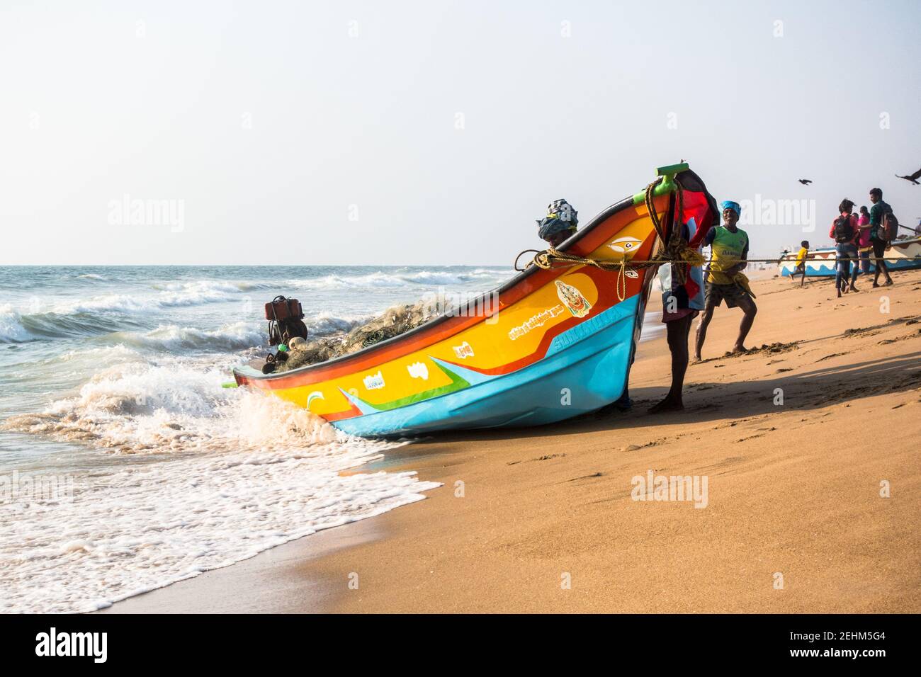 Pescatore che spinge la barca a terra dal mare dopo il ritorno il lavoro di giorno Foto Stock