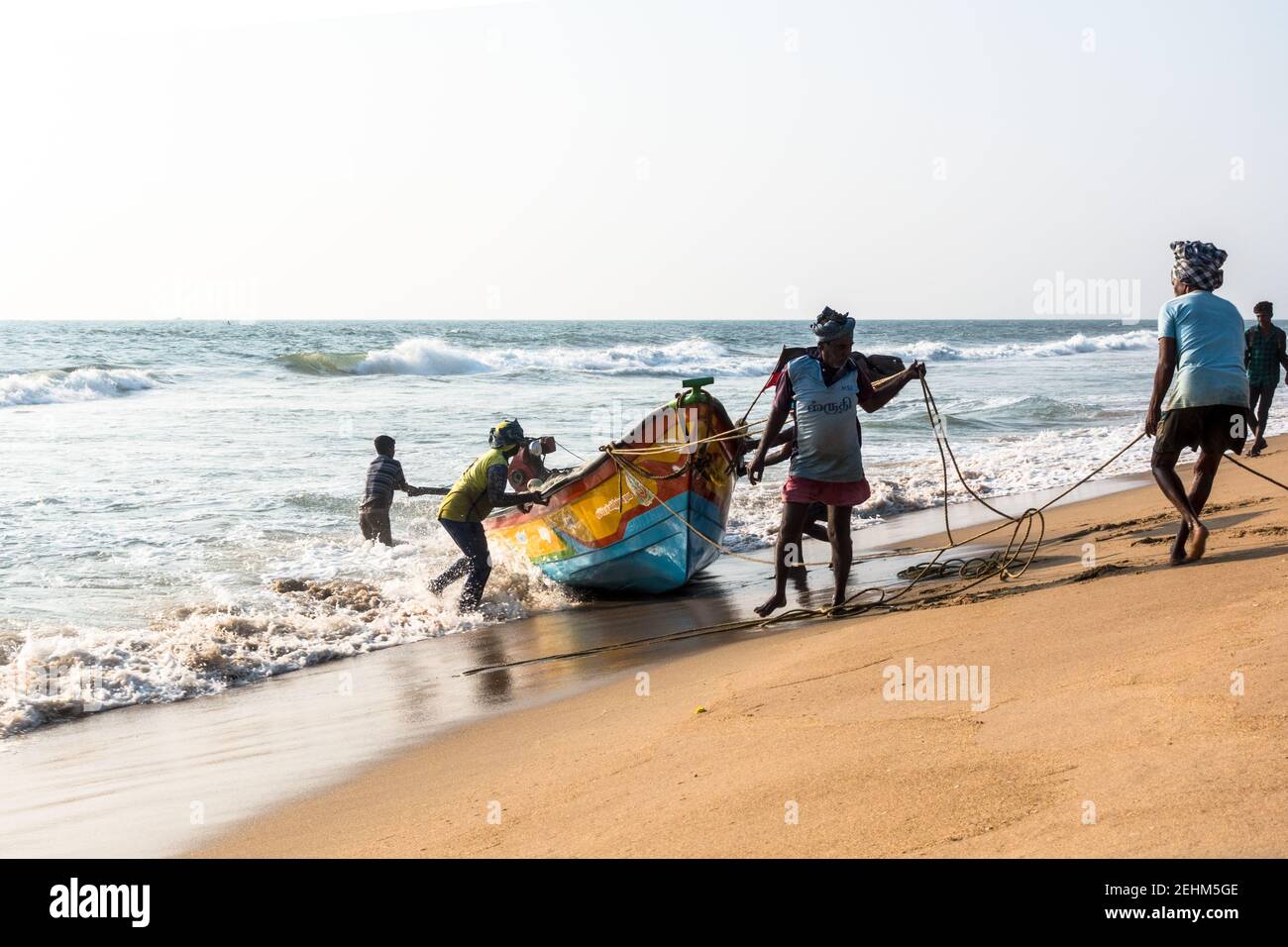 Pescatore che spinge la barca a terra dal mare dopo il ritorno il lavoro di giorno Foto Stock