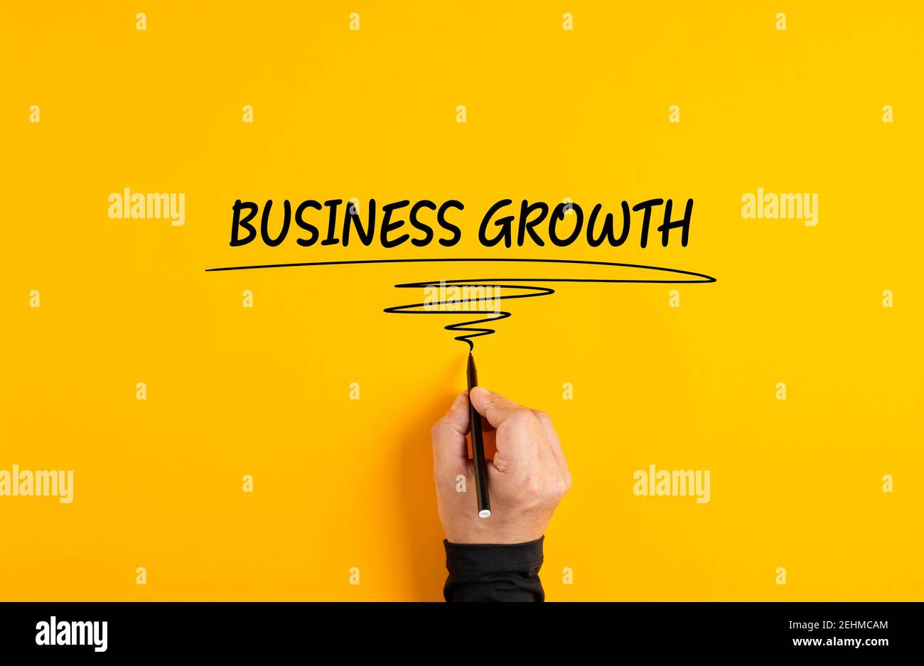 La mano maschio che scrive la crescita di affari di parola su sfondo giallo. Foto Stock