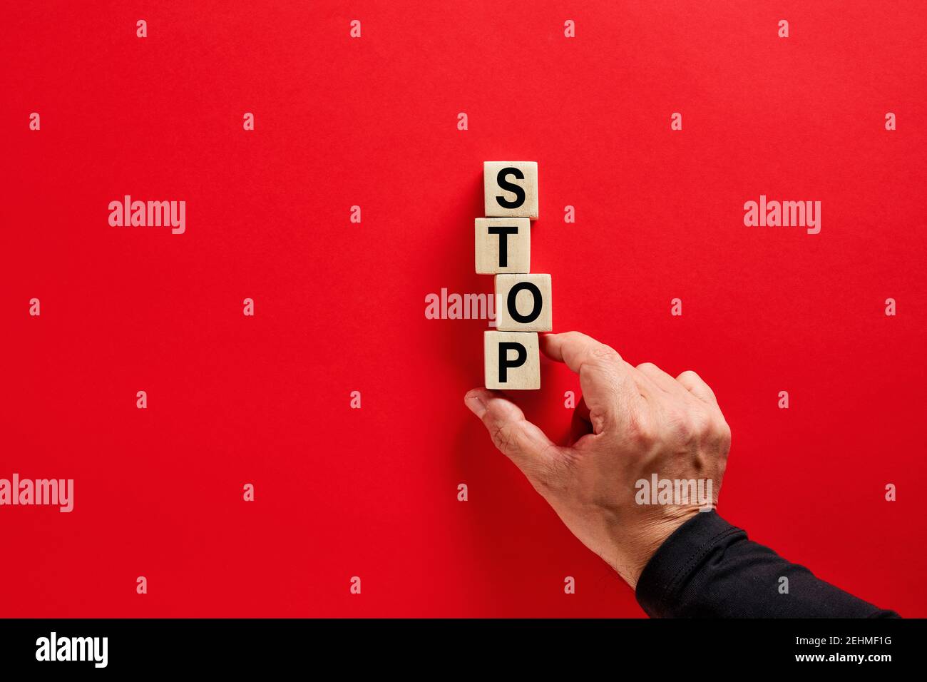 Mano maschile disposizione dei blocchi di legno con la parola stop su sfondo rosso con spazio di copia. Decisione di interrompere o uscire dal concetto. Foto Stock