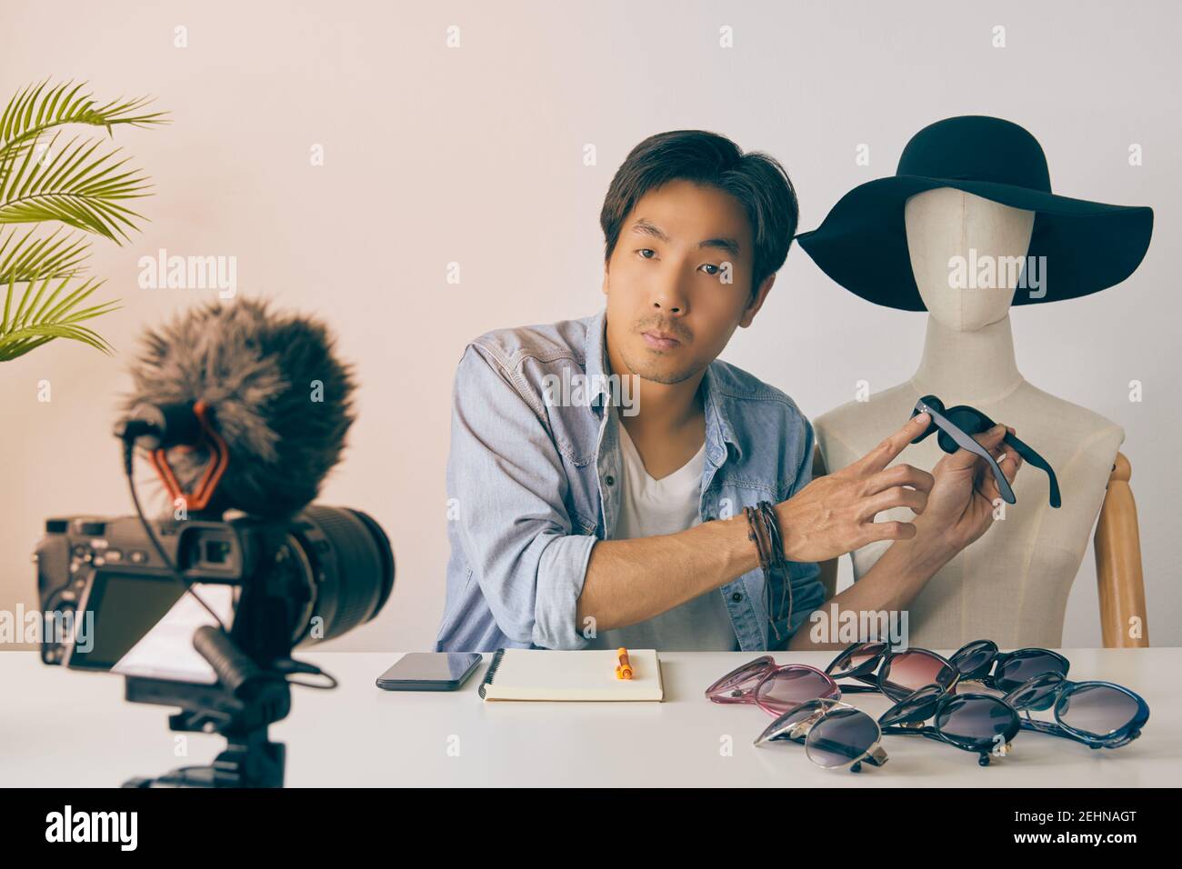 Asian Vlogger o Blogger in camicie Jean con occhiali di moda Mannequins Point e video di registrazione. Freelance Online Live Streaming con il cliente via Foto Stock