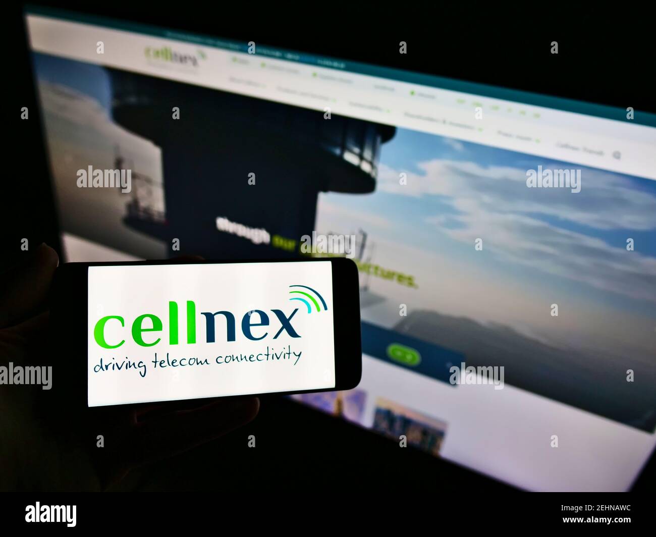 Persona che detiene smartphone con logo della società spagnola di telecomunicazioni Cellnex Telecom S.A. sullo schermo di fronte al sito web. Mettere a fuoco il display del telefono. Foto Stock