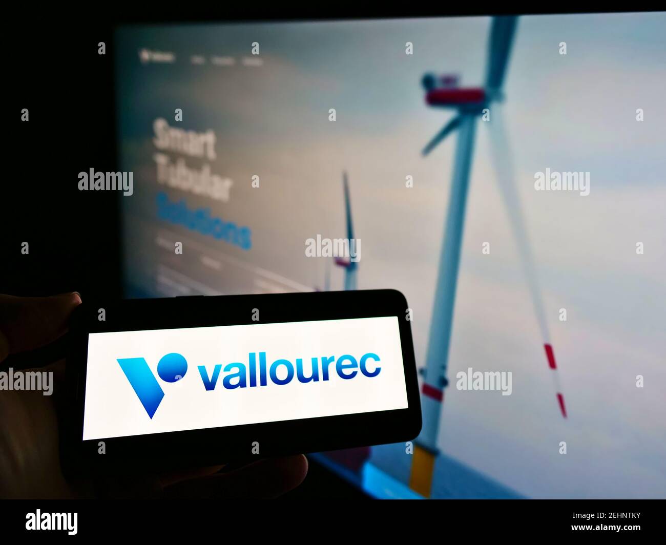 Persona che detiene cellulare con logo aziendale del produttore francese di tubi d'acciaio Vallourec S.A. sullo schermo davanti alla pagina web. Mettere a fuoco il display del telefono. Foto Stock