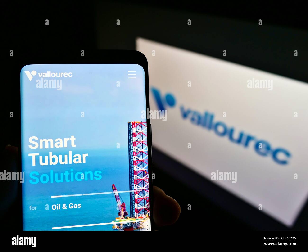 Persona che tiene smartphone con il sito web del produttore francese di tubi d'acciaio Vallourec SA sullo schermo davanti al logo. Mettere a fuoco il centro del display del telefono. Foto Stock