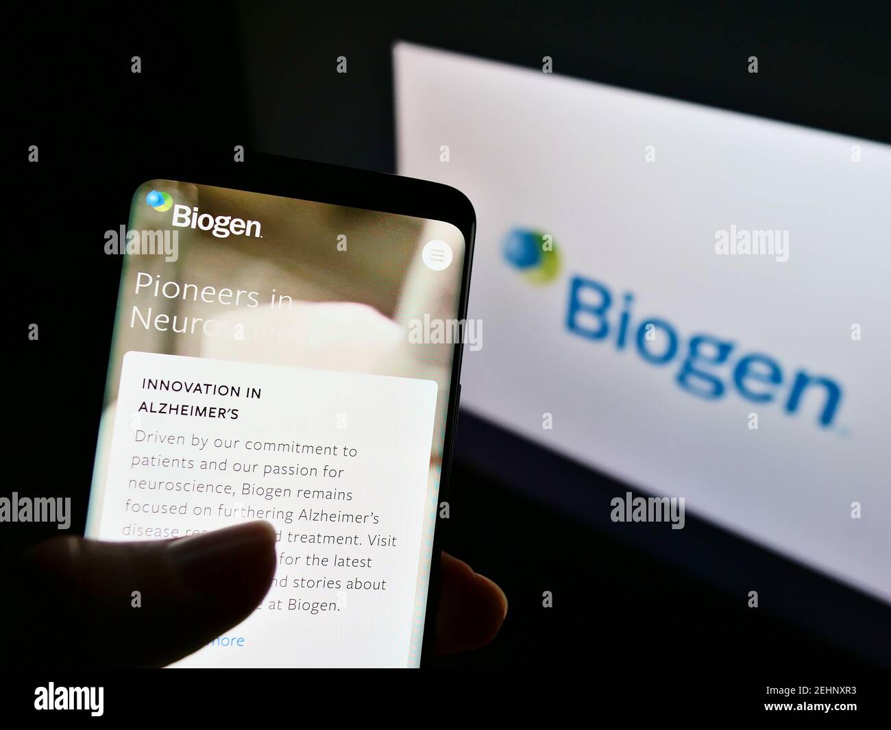 Persona che tiene il telefono mobile con il logo della società di biotecnologia statunitense Biogen Inc. Sullo schermo davanti al sito web. Focus sul centro del display del cellulare. Foto Stock