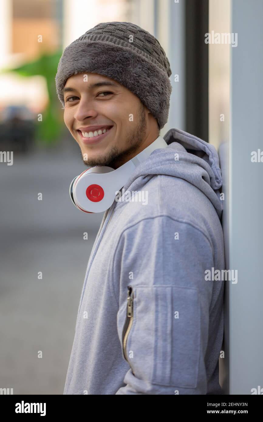 Sorridente giovane latino di allenamento sportivo con cuffie in formato ritratto all'aperto Foto Stock