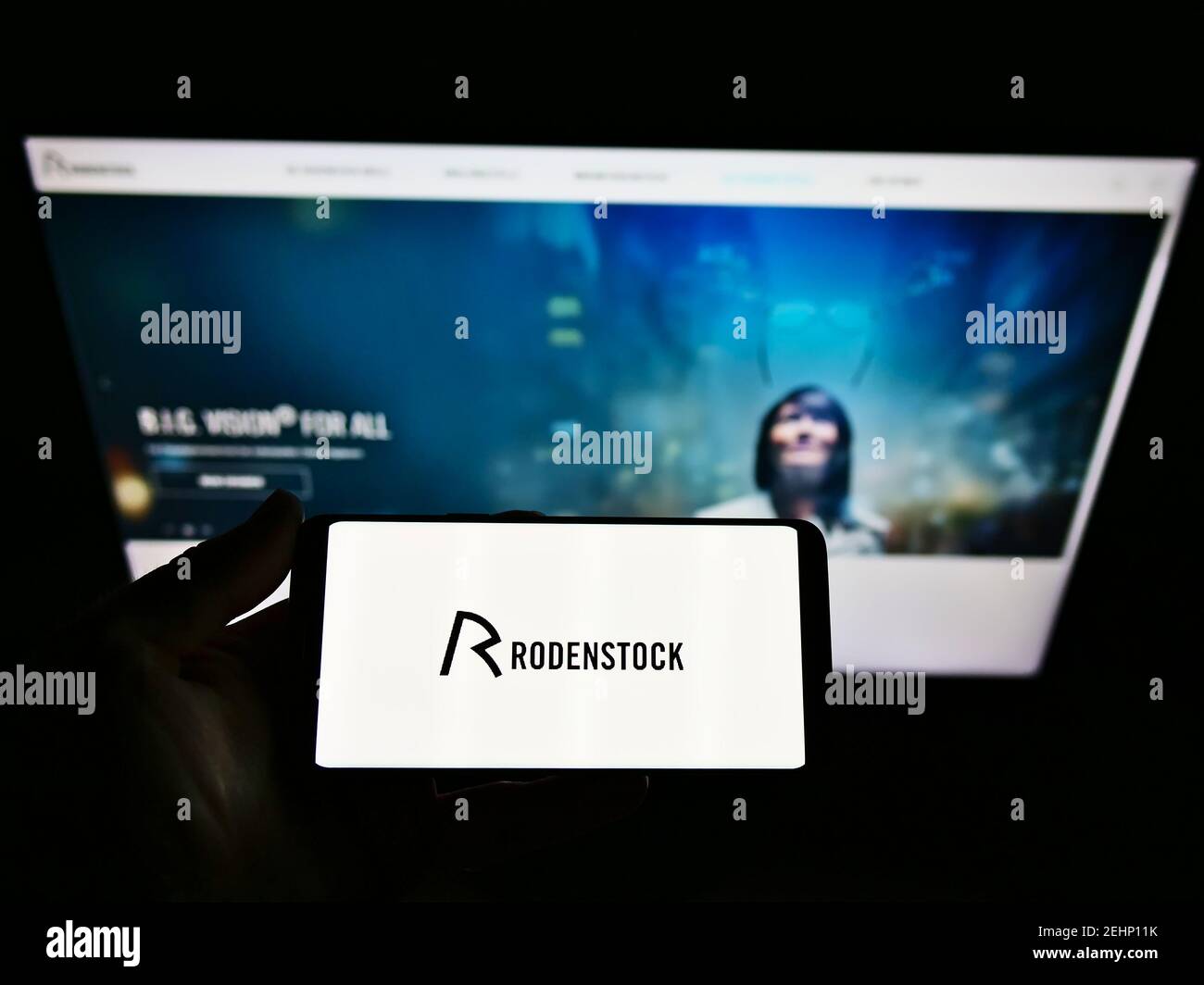 Persona che tiene lo smartphone con il logo del produttore tedesco di occhiali Rodenstock GmbH sullo schermo di fronte al sito web. Mettere a fuoco il display del telefono. Foto Stock