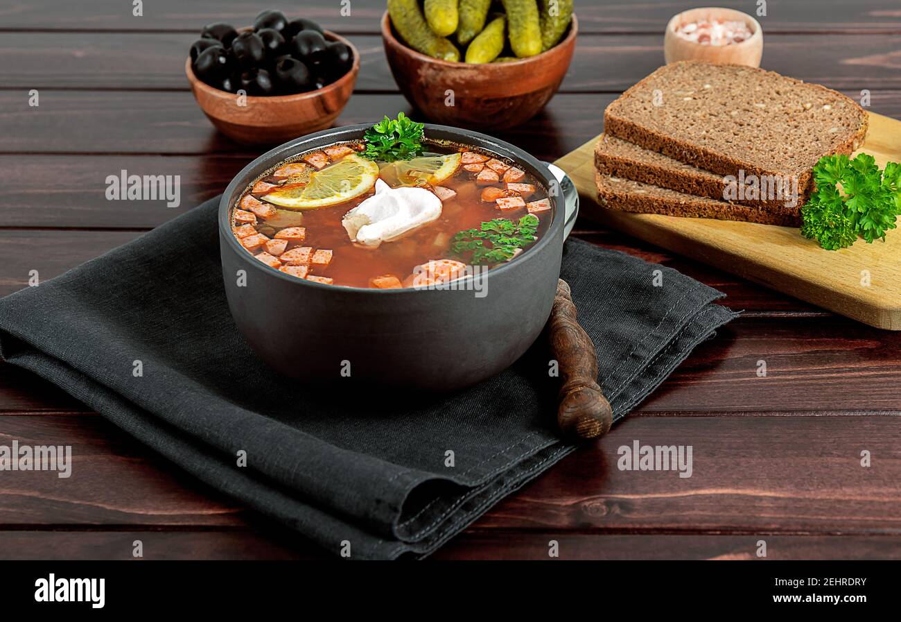 Solyanka o soljanka, zuppa russa ed europea orientale con salsiccia, olive, cetriolo sottaceto e capperi Foto Stock
