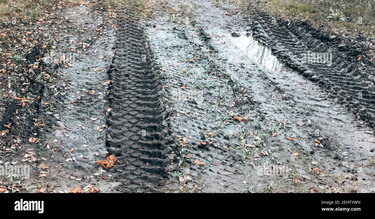 Puddle da una strada sterrata. Paesaggio stradale campagna vuota. Sfondo con contrassegni di strada e pneumatici Foto Stock