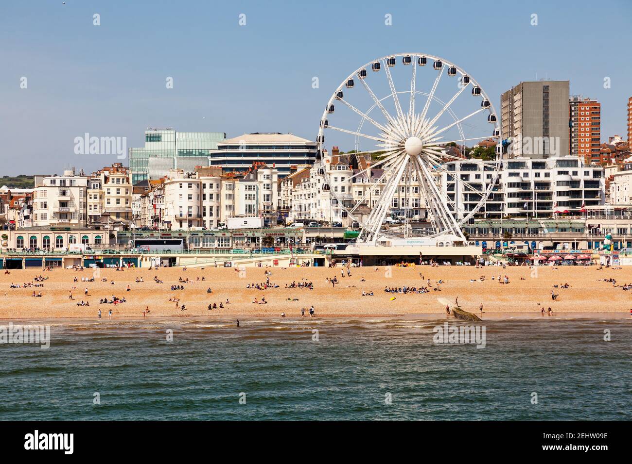 BRIGHTON, Regno Unito - 5 GIU 2013: Holidayers godendo di buone condizioni atmosferiche in corrispondenza di spiaggia di ciottoli vicino alla ruota panoramica su una soleggiata giornata estiva Foto Stock