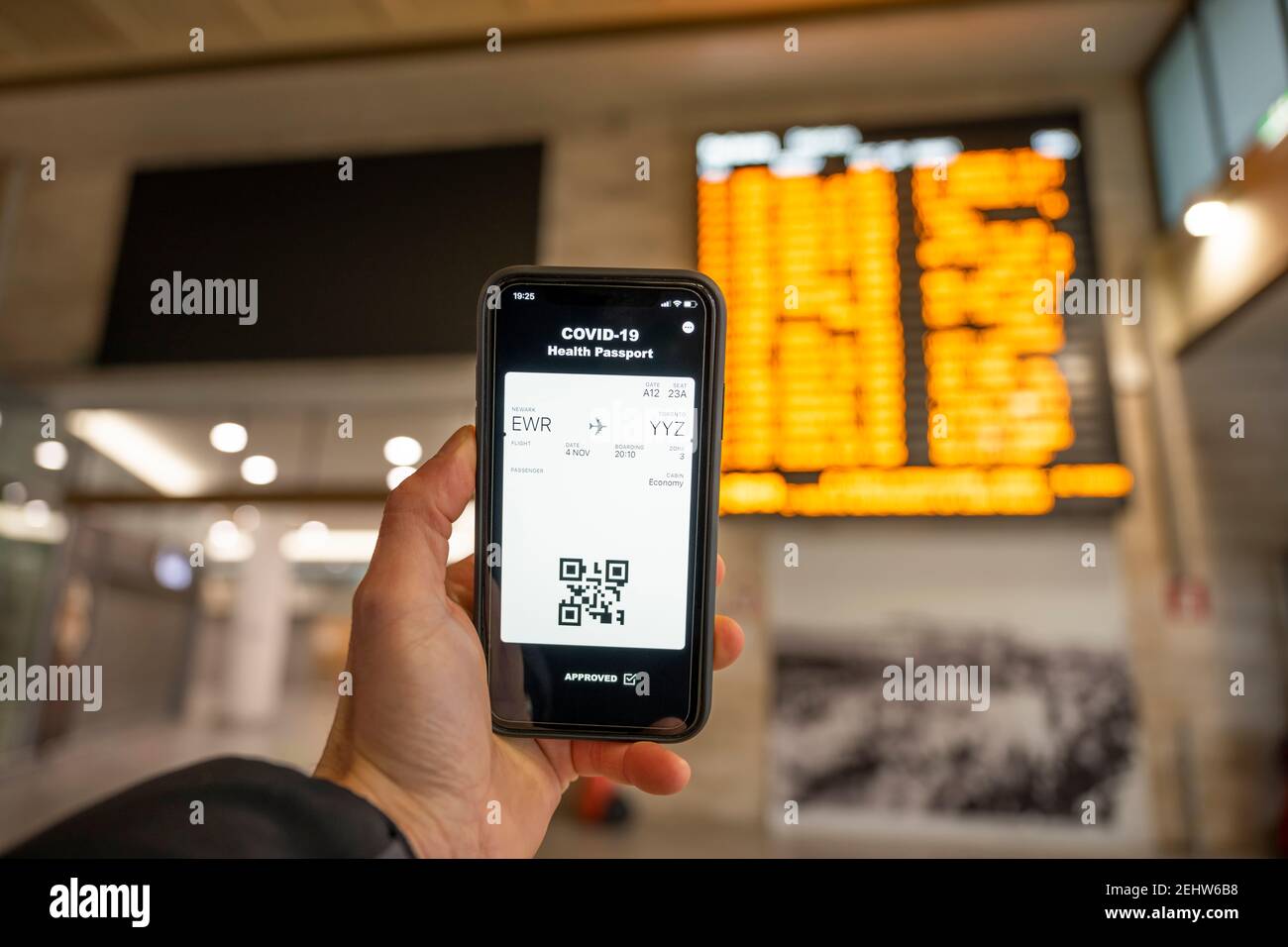 Vista dall'alto di una mano umana che sorregge uno smartphone con un passaporto sanitario digitale e una carta d'imbarco Foto Stock