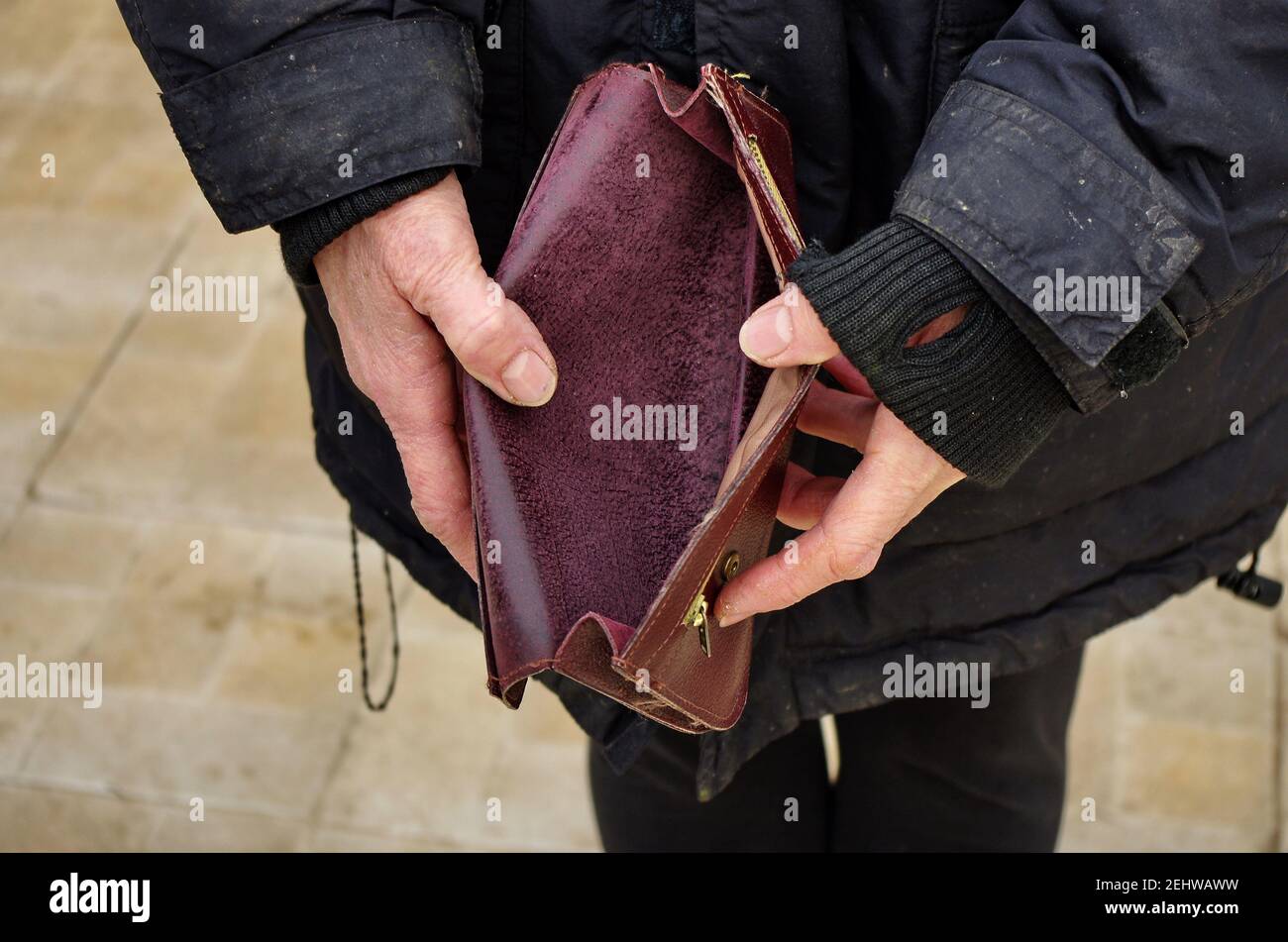 Una donna povera senza casa anziana ha un portafoglio vuoto, o borsetta. Il concetto di povertà in pensione. Povertà estrema globale. Nessun denaro mi aiuta. Foto Stock